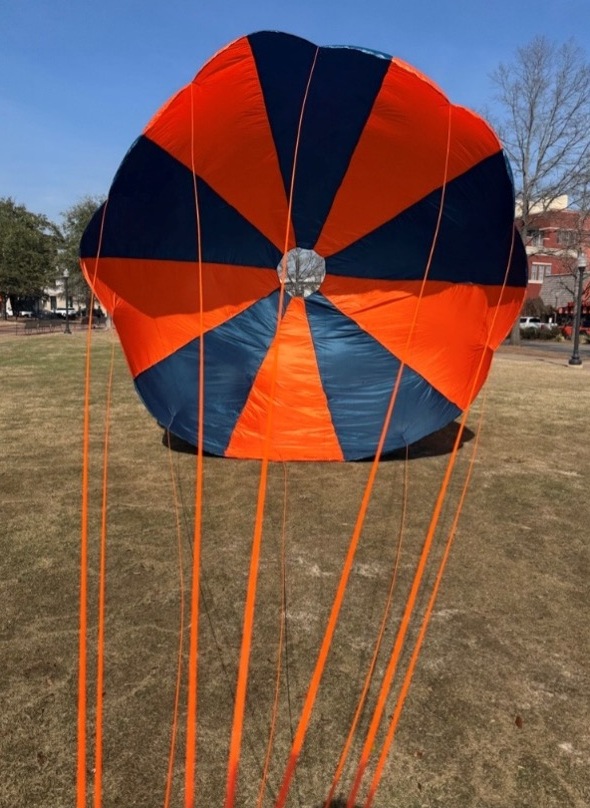 AURA orange and navy parachute deployed on the field